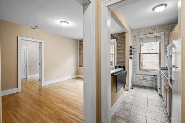 kitchen featuring stainless steel gas stove, light hardwood / wood-style flooring, and brick wall