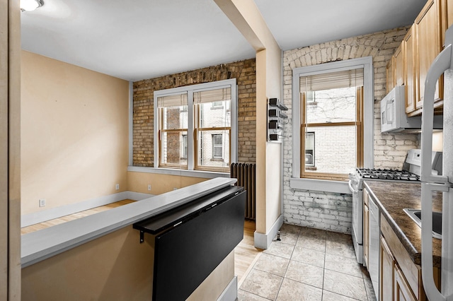 kitchen featuring plenty of natural light, light brown cabinets, gas range oven, and light tile patterned floors