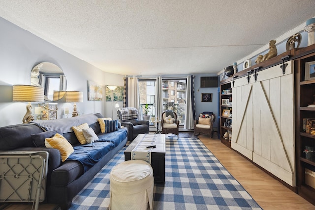 living room featuring hardwood / wood-style flooring, a barn door, and a textured ceiling