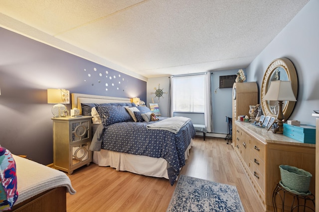 bedroom with a baseboard radiator, light hardwood / wood-style floors, and a textured ceiling