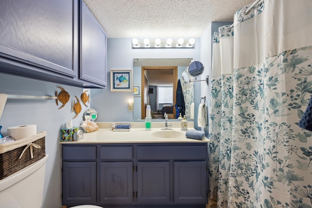 bathroom with a shower with curtain, vanity, a textured ceiling, and toilet