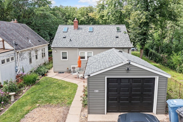 back of house featuring an outbuilding, a garage, a lawn, and a patio area