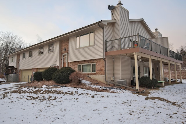 view of snowy exterior with a balcony and cooling unit