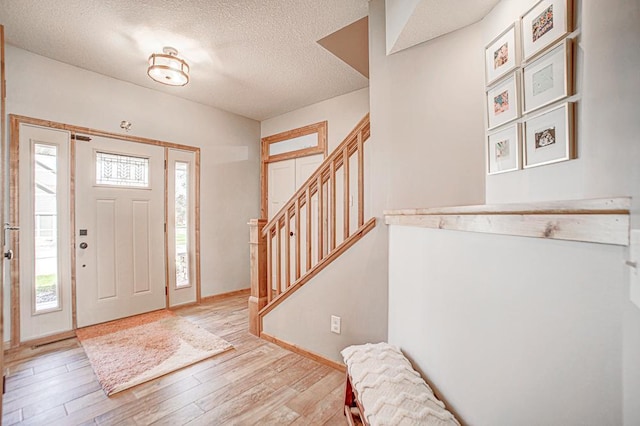 entryway with a textured ceiling and light wood-type flooring