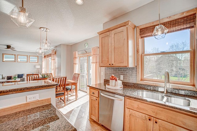 kitchen with sink, stainless steel dishwasher, hanging light fixtures, and light brown cabinets