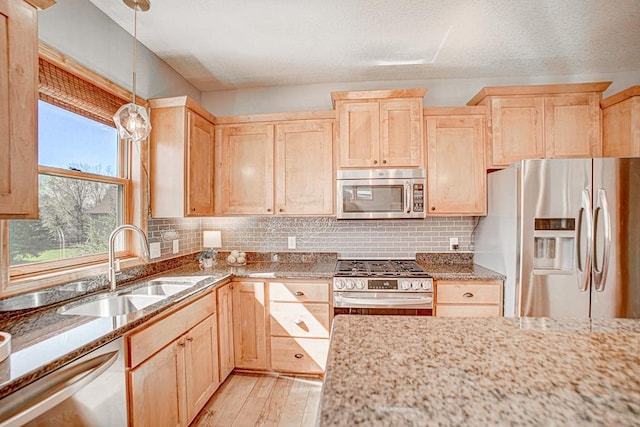 kitchen featuring pendant lighting, light hardwood / wood-style flooring, stainless steel appliances, tasteful backsplash, and light brown cabinets