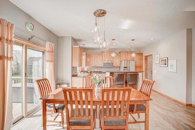 dining room with a textured ceiling and light wood-type flooring