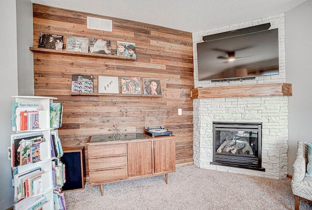 interior space with light colored carpet, a fireplace, and wood walls