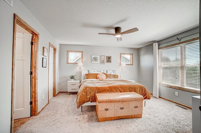 bedroom featuring ceiling fan, light colored carpet, and a textured ceiling