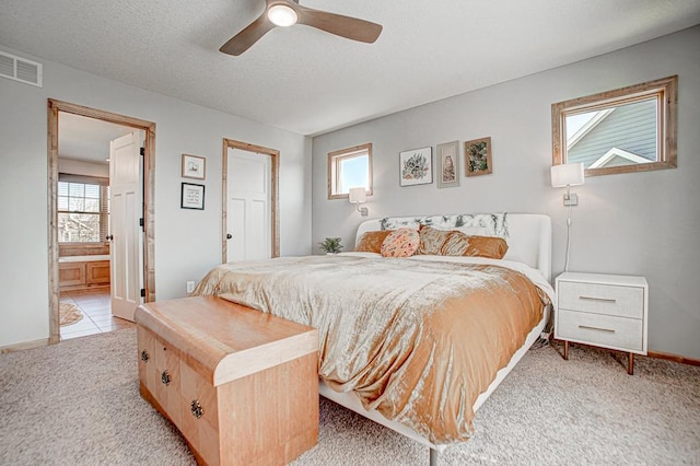 carpeted bedroom featuring multiple windows, ceiling fan, connected bathroom, and a textured ceiling