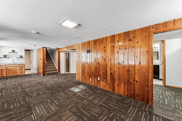 carpeted empty room featuring sink and wooden walls