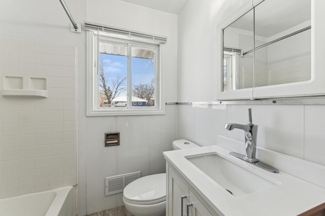 full bathroom with vanity, tiled shower / bath combo, tile walls, and toilet