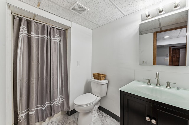 bathroom with a shower with curtain, vanity, a drop ceiling, and toilet