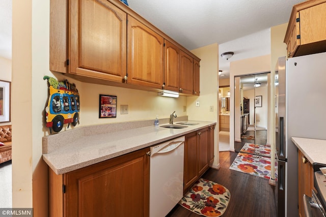 kitchen featuring dishwasher, sink, stainless steel fridge, dark wood-type flooring, and a textured ceiling