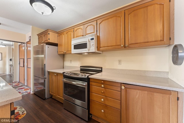 kitchen with appliances with stainless steel finishes and dark hardwood / wood-style flooring