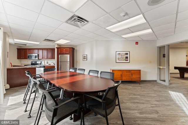 dining room featuring a drop ceiling, light hardwood / wood-style flooring, and a baseboard radiator