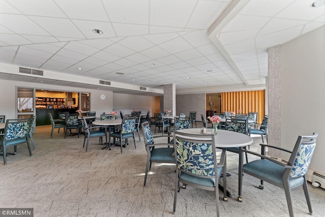 dining room featuring a drop ceiling and carpet