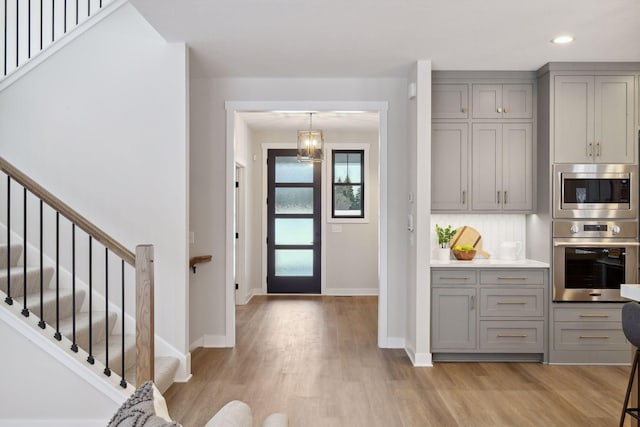 kitchen featuring stainless steel appliances, tasteful backsplash, gray cabinetry, and light hardwood / wood-style flooring