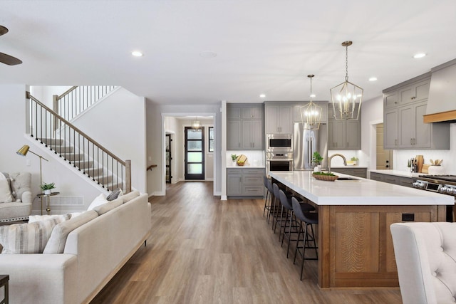 kitchen with pendant lighting, sink, a breakfast bar, gray cabinetry, and stainless steel appliances