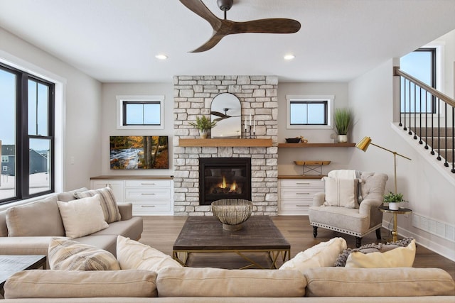 living room featuring wood-type flooring, ceiling fan, and a fireplace