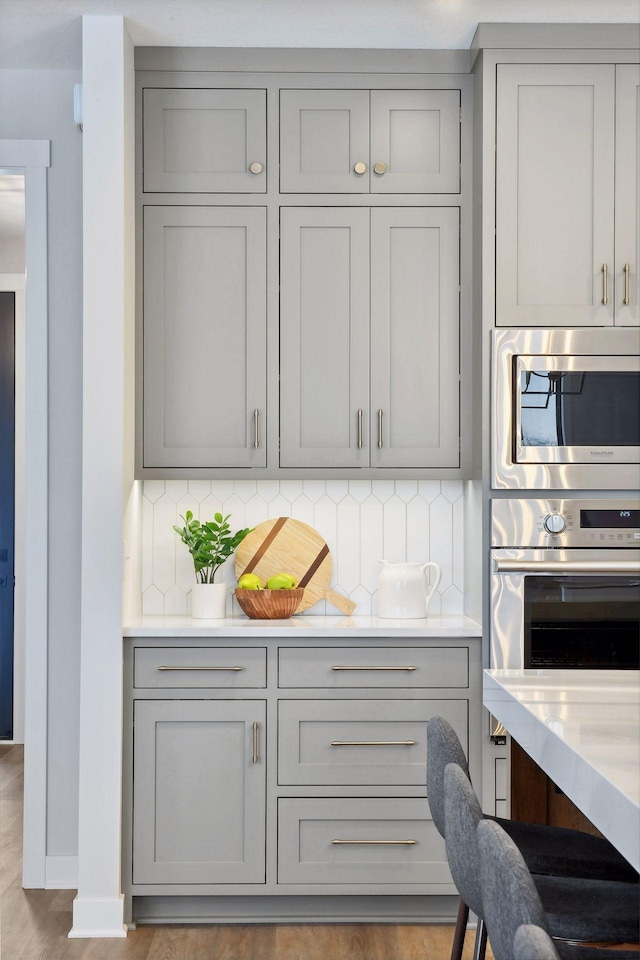 kitchen featuring tasteful backsplash, appliances with stainless steel finishes, and gray cabinets