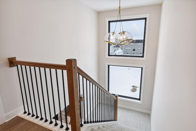 staircase featuring hardwood / wood-style flooring, plenty of natural light, and an inviting chandelier