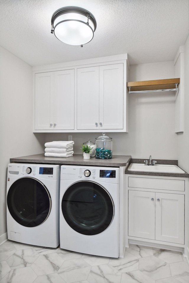 laundry room featuring cabinets, washer and clothes dryer, sink, and a textured ceiling