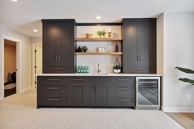 bar featuring beverage cooler, sink, and light wood-type flooring