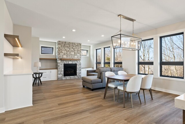 18436 56th Ct N, Plymouth, MN 55446 - dining space with light wood-style flooring, a chandelier, a fireplace, recessed lighting, and baseboards