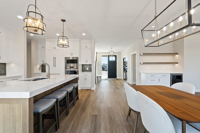18436 56th Ct N, Plymouth, MN 55446 - kitchen featuring a sink, recessed lighting, beverage cooler, backsplash, and wood finished floors