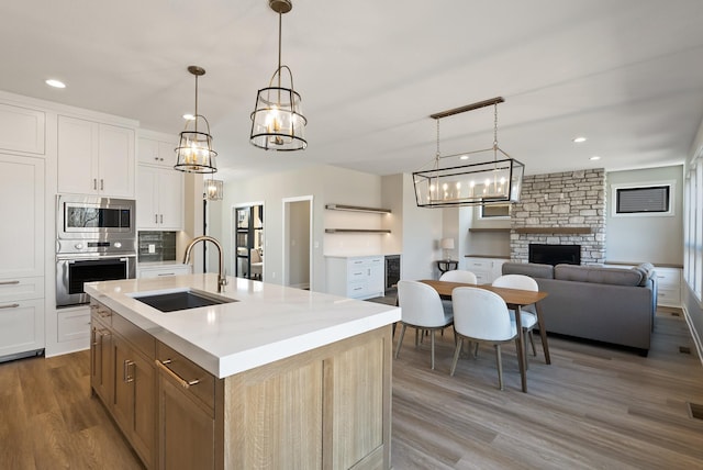 18436 56th Ct N, Plymouth, MN 55446 - kitchen featuring appliances with stainless steel finishes, a sink, wood finished floors, light countertops, and a fireplace