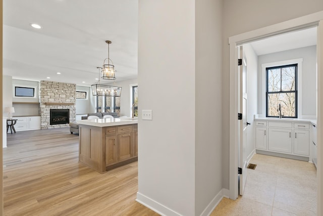 18436 56th Ct N, Plymouth, MN 55446 - kitchen with a stone fireplace, a sink, light countertops, open floor plan, and hanging light fixtures