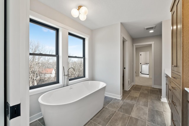 18436 56th Ct N, Plymouth, MN 55446 - bathroom with washer / dryer, baseboards, and a freestanding tub
