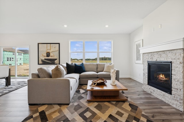 living room with dark hardwood / wood-style flooring and a stone fireplace