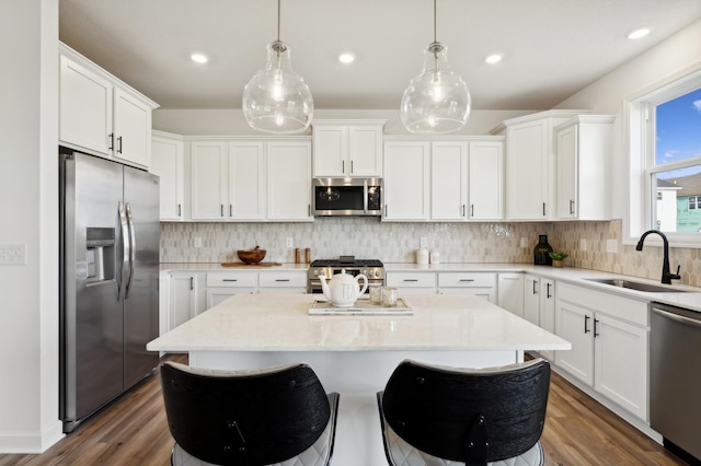 kitchen featuring a center island, appliances with stainless steel finishes, sink, white cabinets, and pendant lighting