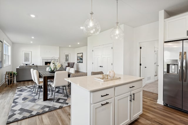 kitchen with a center island, white cabinetry, hanging light fixtures, and stainless steel refrigerator with ice dispenser