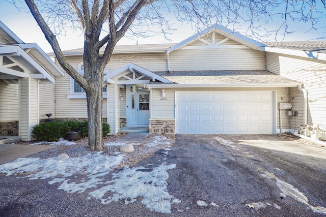 view of front facade featuring aphalt driveway, roof with shingles, and an attached garage