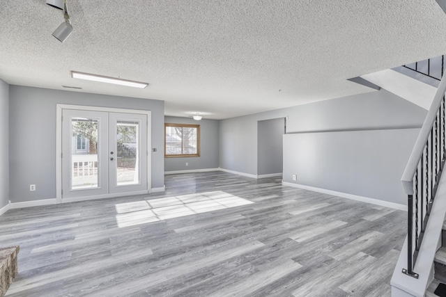 unfurnished living room with french doors, wood finished floors, and baseboards