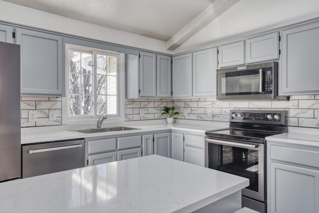 kitchen with stainless steel appliances, a sink, decorative backsplash, and light stone countertops