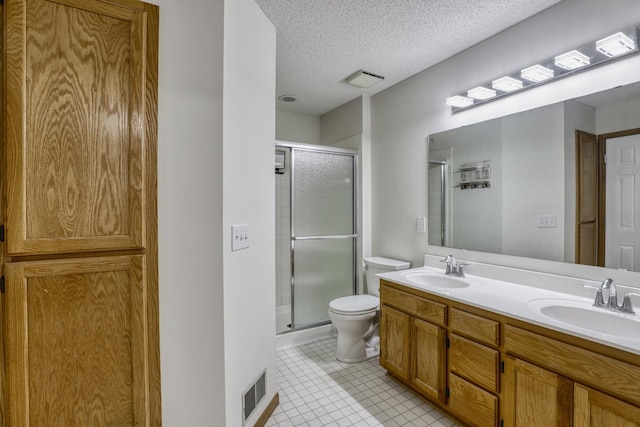 bathroom with double vanity, a shower stall, a textured ceiling, and a sink