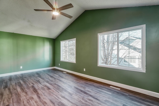 unfurnished room featuring lofted ceiling, baseboards, visible vents, and wood finished floors