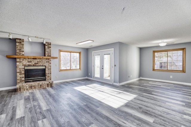 unfurnished living room featuring french doors, a fireplace, wood finished floors, and baseboards