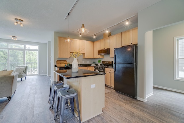 kitchen with a kitchen breakfast bar, light brown cabinets, light hardwood / wood-style flooring, a center island, and black appliances