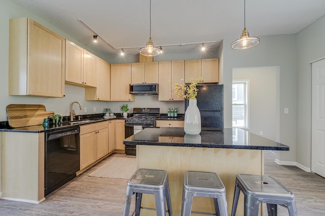 kitchen with light brown cabinetry, sink, a kitchen bar, a center island, and black appliances