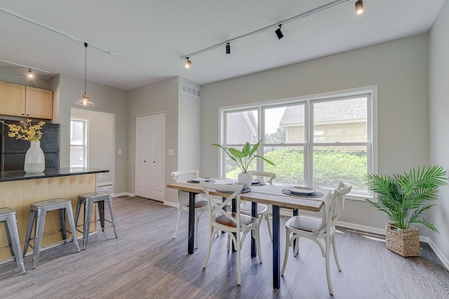 dining room with rail lighting, a textured ceiling, and light wood-type flooring