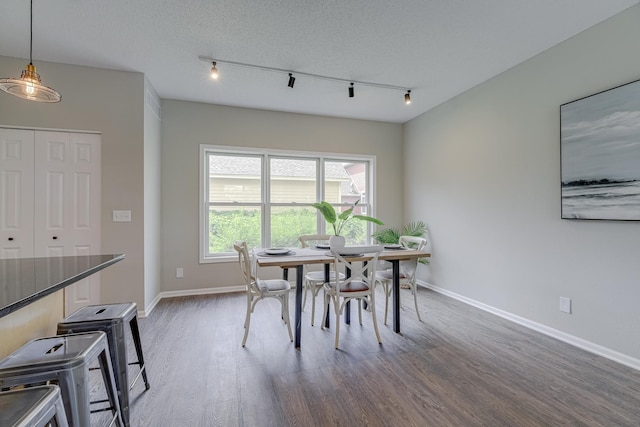 dining space with a textured ceiling, dark hardwood / wood-style floors, and track lighting