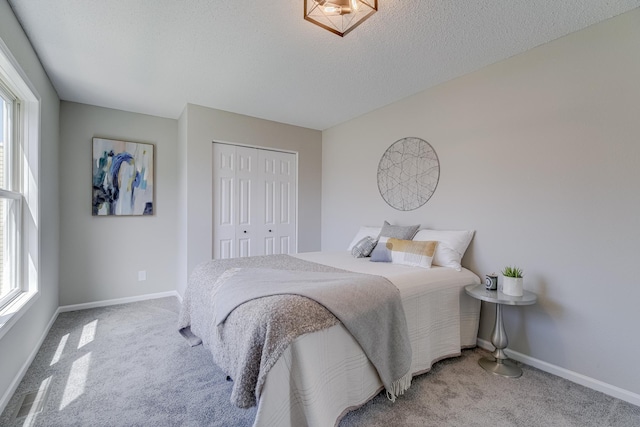 bedroom with light colored carpet, a textured ceiling, and a closet