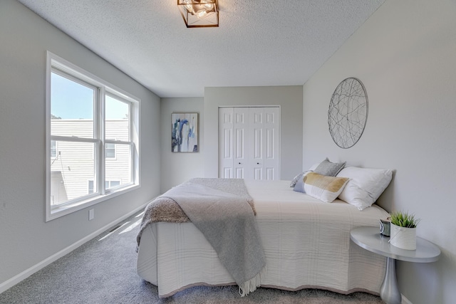 bedroom with a textured ceiling, carpet flooring, and a closet