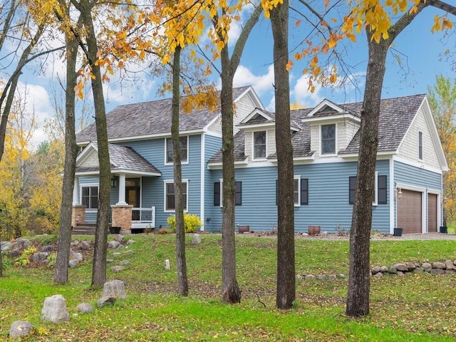 view of side of property featuring a porch, a yard, and a garage