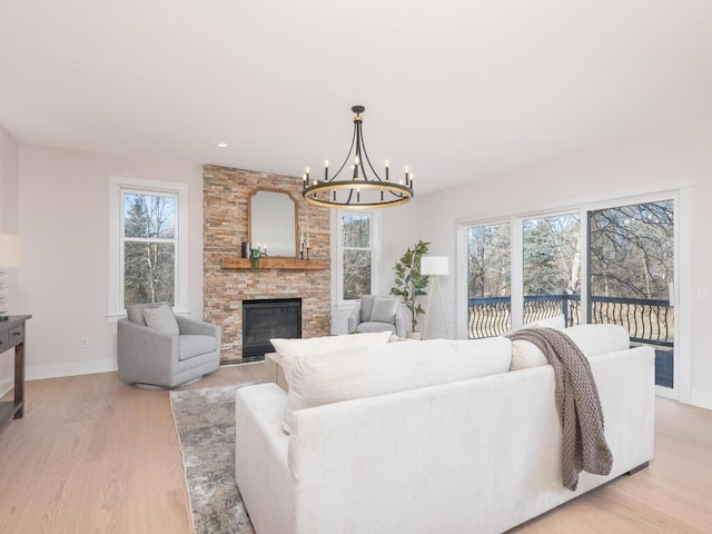 living room featuring an inviting chandelier, a fireplace, and light hardwood / wood-style flooring